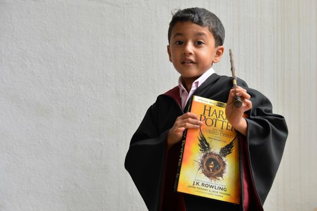 I bambini che leggono Harry Potter diventeranno delle persone tolleranti Un bambino, vestito da mago, con in mano la bacchetta e un libro di Harry Potter