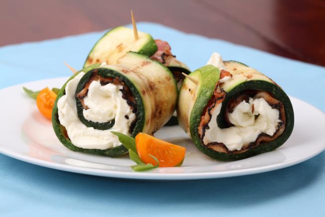involtini di zucchine alla griglia con speck e crema di formaggio: la ricetta Primo piano su piatto bianco di zucchine alla griglia ripiene di speck e crema di formaggio