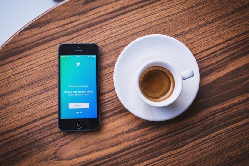 Emoji e struttura a due colonne: Twitter cambia la veste grafica della versione web. Uno smartphone con Twitter e una tazza di caffè.
