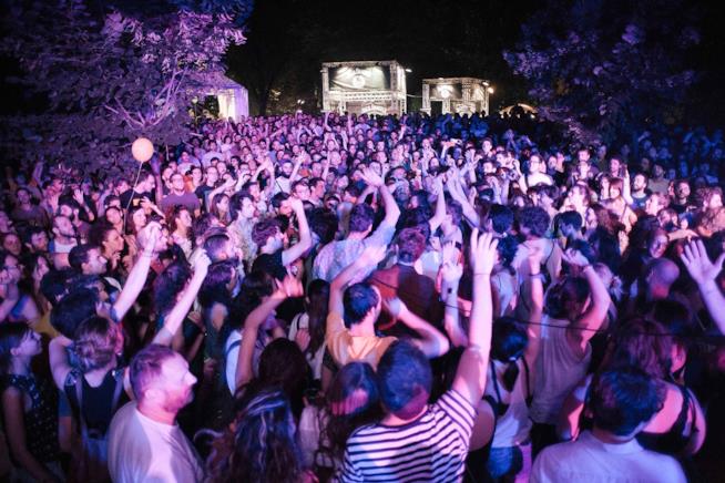 Il pubblico del Mi Ami Ragazzi con le mani alzate, ai lati gli alberi e in lontananza due palchi