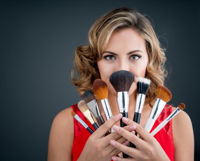 donna con pennelli per trucco Una donna mostra alcunu pennelli per applicare il fondotinta