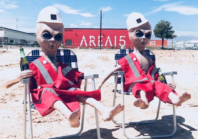 Il festival Alien Stock per l'Area 51 cambia location, ma perde un organizzatore Due alieni di gomma con sullo sfondo la sede della società di intrattenimento Area 15