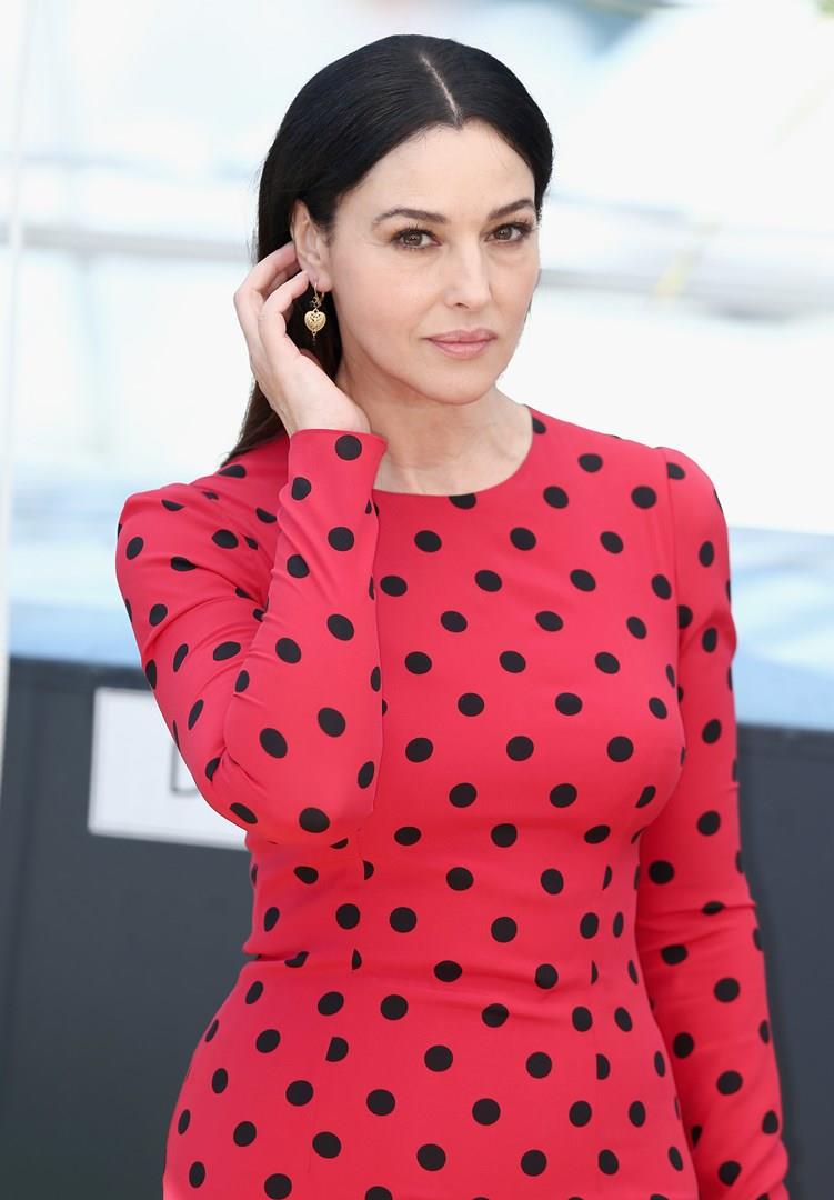 Monica Bellucci, neo membro dell'Academy, indossa un abito rosso a pois neri Uno scatto di Monica Bellucci in abito rosso a pois neri, mentre si sistema i capelli dietro l'orecchio