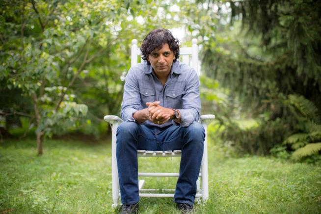 M. Night Shyamalan regista di Eleven Little Indians M. Night Shyamalan su una sedia in giardino