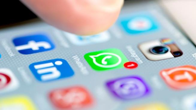 WhatsApp nuovo aggiornamento per la gestione delle notifiche Un dito sul display sta per schiacciare l'icona di WhatdsApp