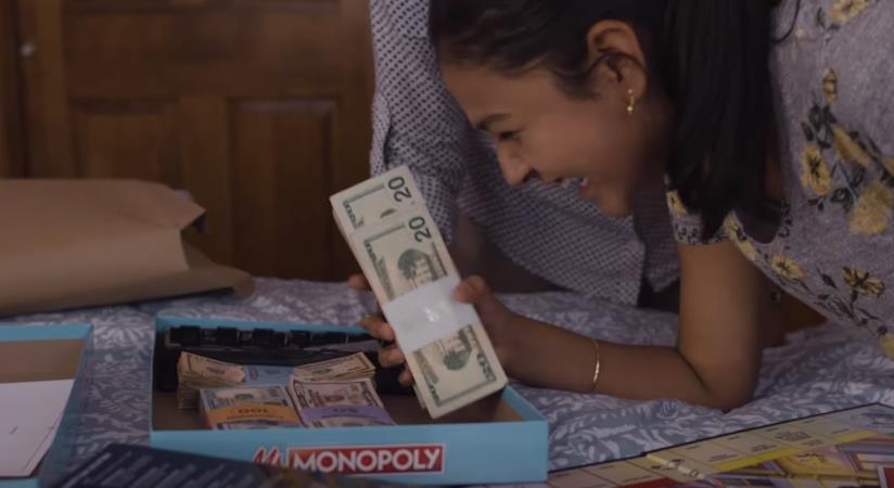 Il gioco del Monopoly ha una nuova versione, tutta al femminile Una ragazza ride mentre tiene in mano delle banconote contenute nel Monopoly al femminile