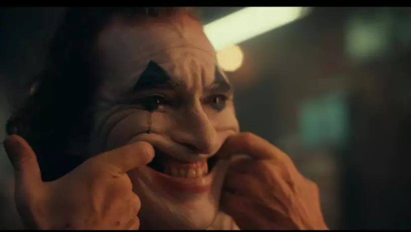 Joaquin Phoenix confessa di essere stato inizialmente spaventato dal ruolo di Joker Un primo piano di Joaquin Phoenix col trucco di Joker mentre prova il sorriso in una scena del film