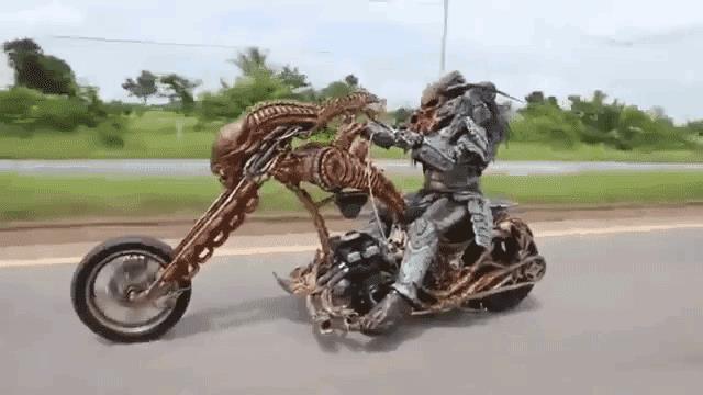 Un cosplayer di Predator a cavallo di una moto in versione Alien Cosplay di Predator