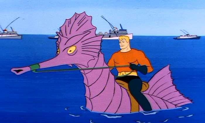 Aquaman è una macchietta che si ritrova in situazioni surreali Aquaman in groppa a un ippocampo gigante viola, con navi sullo sfondo