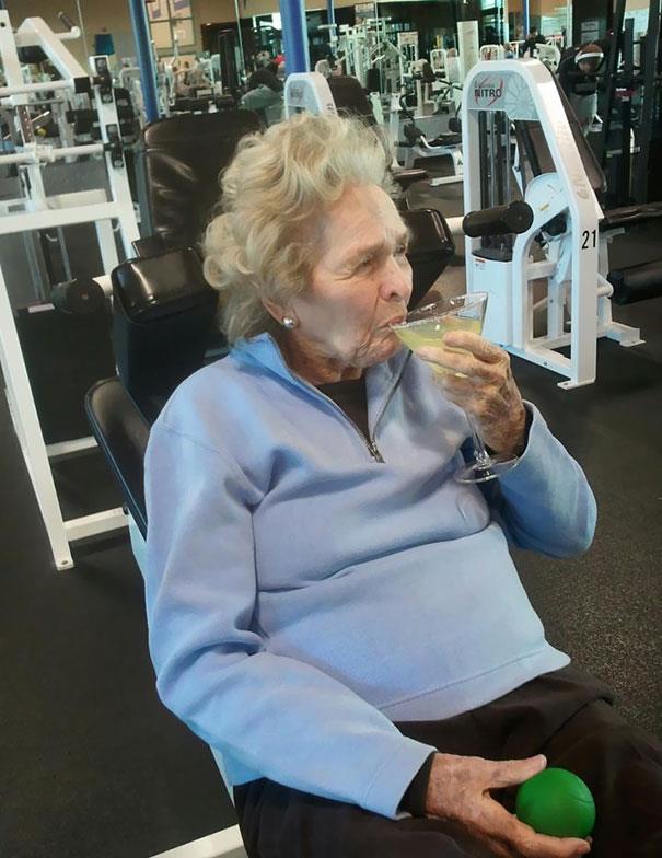 Anziana sorseggia un drink in palestra Primo piano di un'anziana che sorseggia un drink in palestra