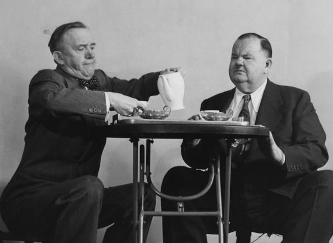 La coppia di comici più famosa della storia del cinema Stan Laurel e Oliver Hardy seduti a un tavolino, mentre il prim oversa del tè al secondo
